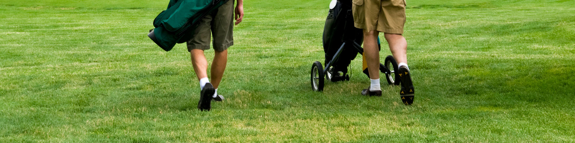 Two men walk on a golf course
